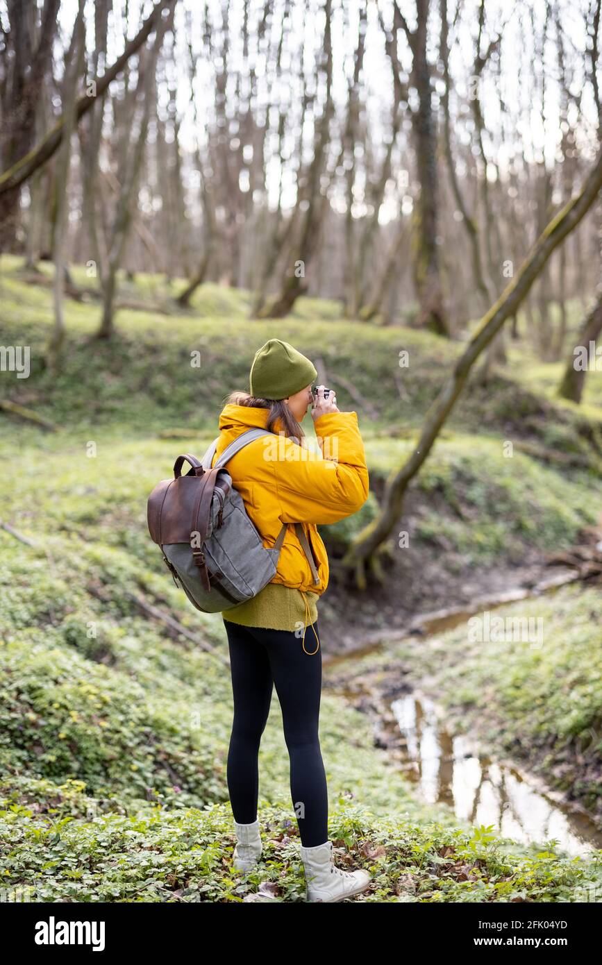 Woman in hiking clothes with backpack takes picture of green