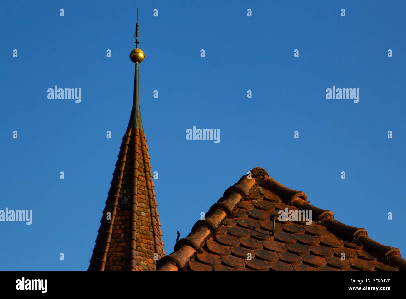 Close up of a rooftop and a church spire against clear blue sky Stock Photo