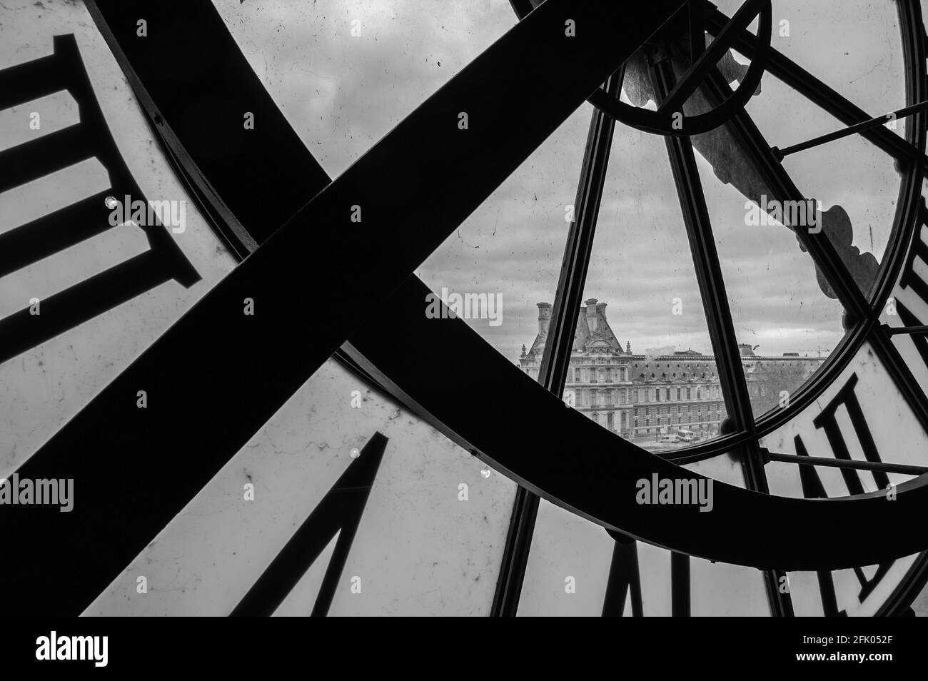 PARIS, FRANCE - APRIL 6, 2014: A clock with roman numerals in the museum D'Orsay and the view on the Louvre museum. Musee d'Orsay has the largest coll Stock Photo
