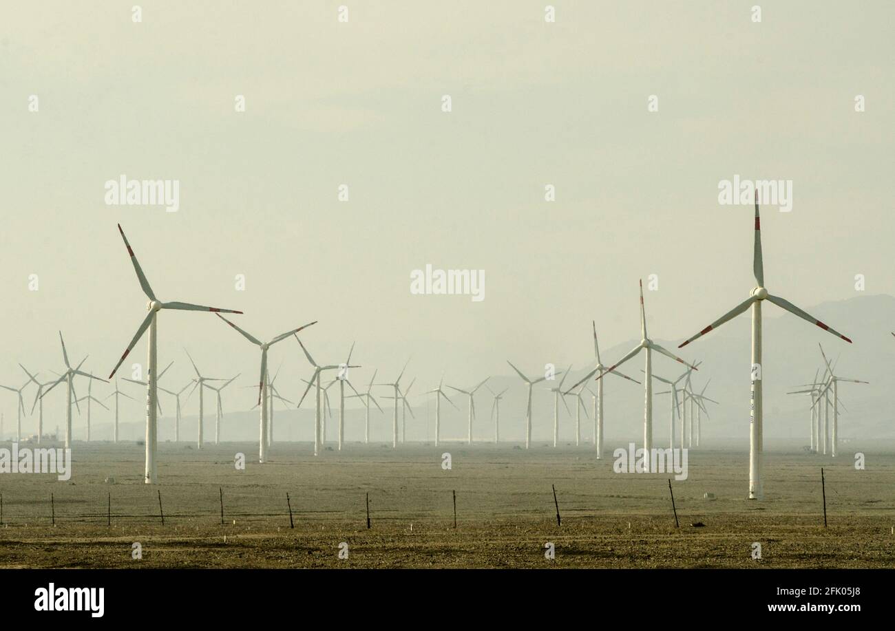 Wind turbines and power lines crisscross the desert on the western outskirts of Turpan, in one of the hottest places on earth. Renewable energy from wind is increasingly used by the Chinese to expand their power-hungry industries, as seen here in Eastern Xinjiang, China, PRC. © Time-Snaps Stock Photo