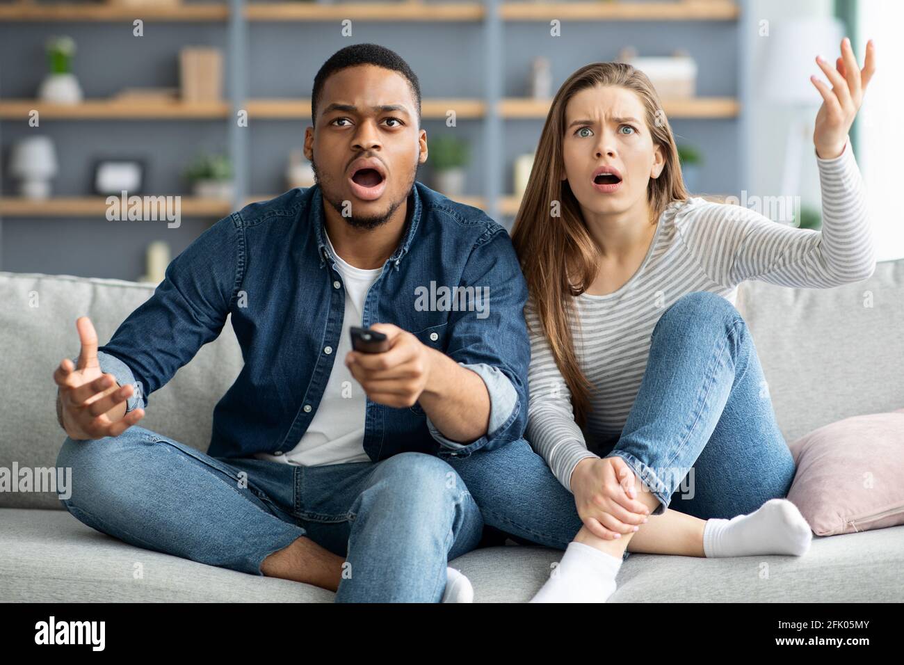 Shocking Tv Programm. Dazed Interracial Couple Watching Tv With Opened  Mouth, Confused Multicultural Spouses Emotionally Reacting To News Program,  Sit Stock Photo - Alamy