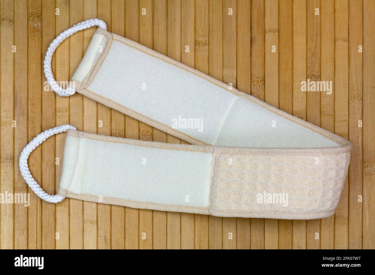 Back scrubbing soft towel strap to rub exfoliating skin during shower with 2 rope to pull, on wooden background Stock Photo