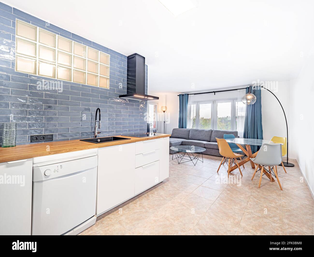 https://c8.alamy.com/comp/2FK0BM8/open-space-kitchen-with-white-cabinets-and-blue-tiles-next-to-the-living-roomspacious-modern-fully-equipped-appliance-interior-with-wooden-desk-brig-2FK0BM8.jpg