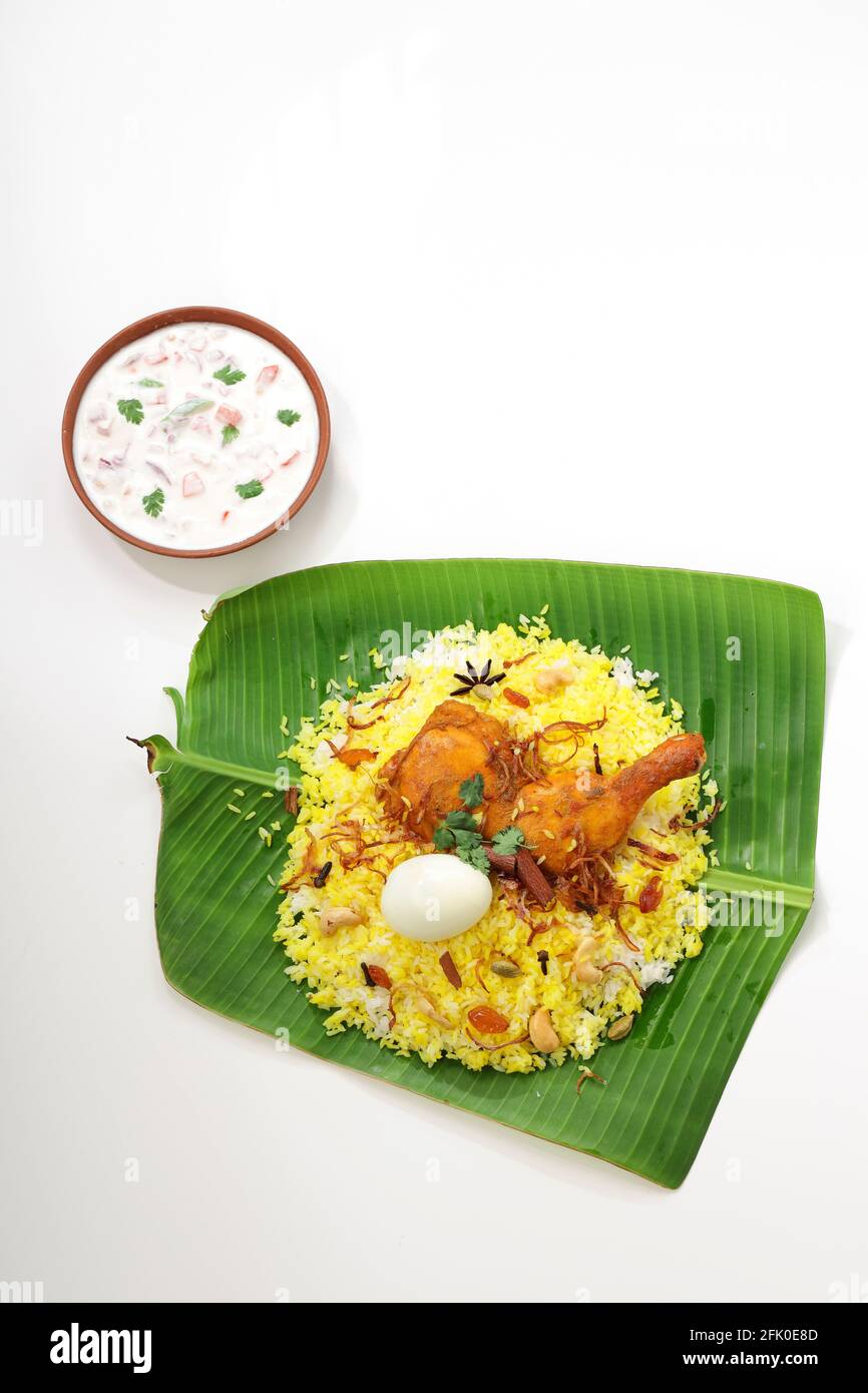 Kerala Chicken dum biryani ,arranged traditionally in a banana leaf  and raita as side dish with white  background or texture,selective focus Stock Photo