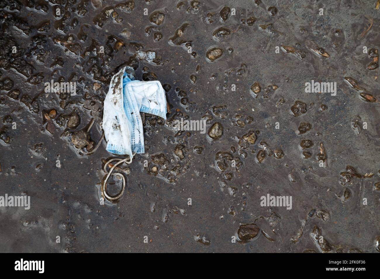 Photo of throwed used medical mask in the dirt Stock Photo