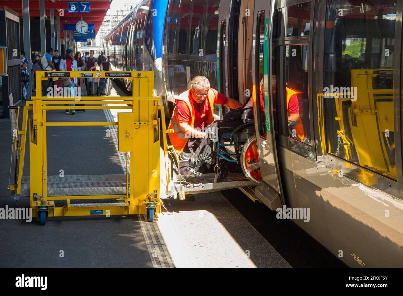 A railway worker helps a disabled passenger alighting from the train at