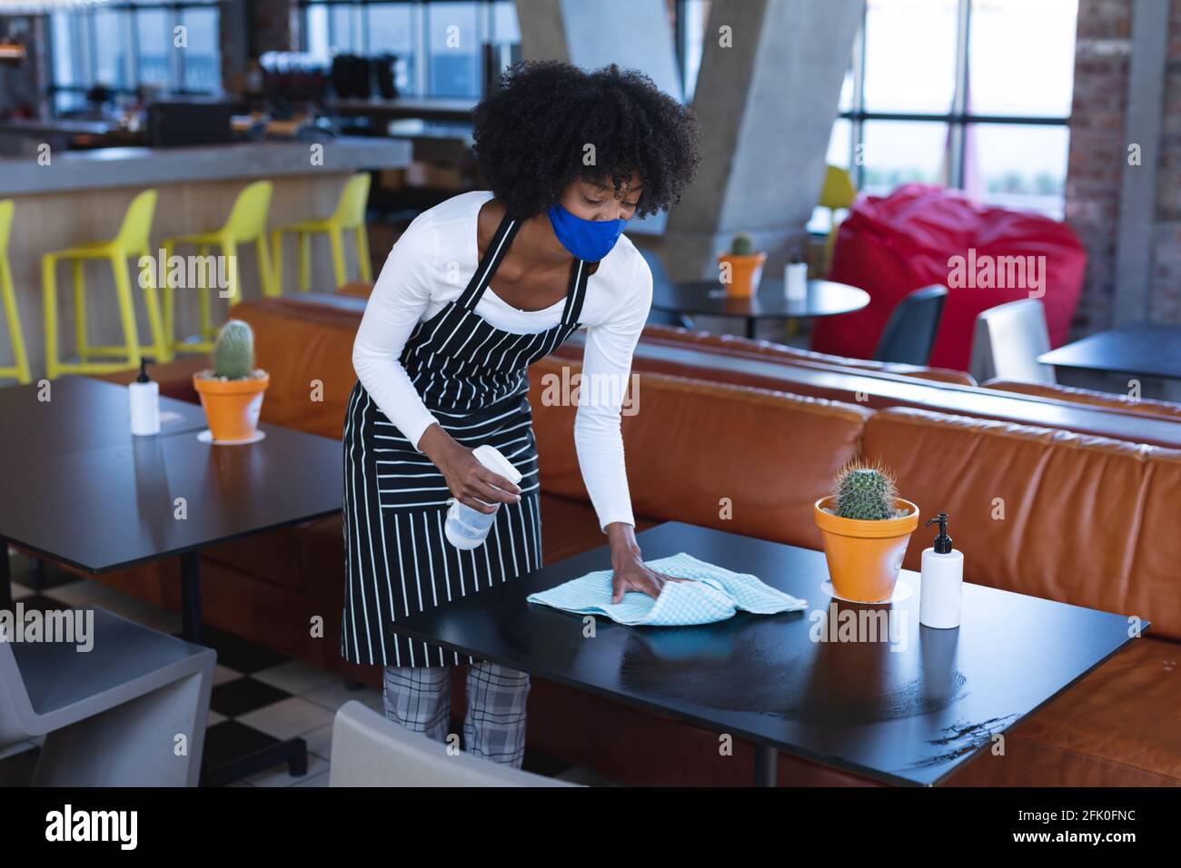 African american woman waitress wearing face mask, disinfecting tables in  cafe Stock Photo - Alamy