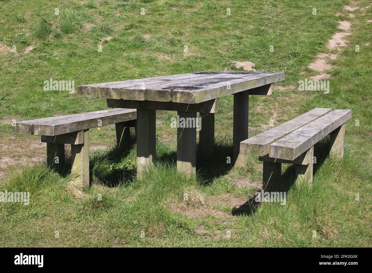 Well used solid wooden picnic table and two wooden benches at Lane Ends Amenity area, a public area adjacent to the sea wall in Pilling, Lancashire. Stock Photo