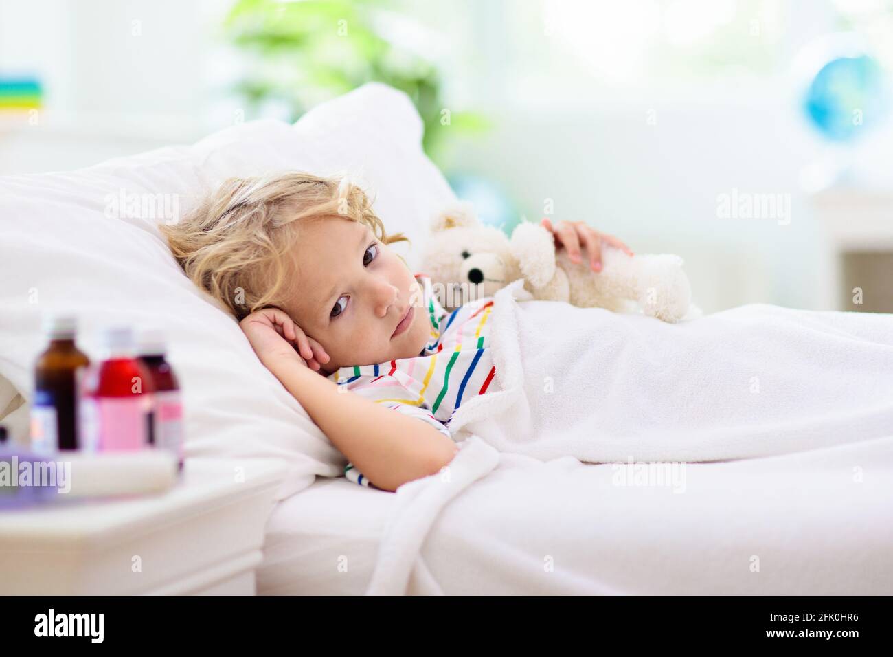 Sick little boy with asthma medicine. Ill child lying in bed. Unwell