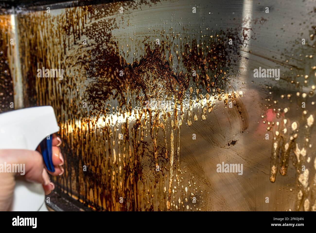 A woman spraying a corner glass pane covered in soot in a modern