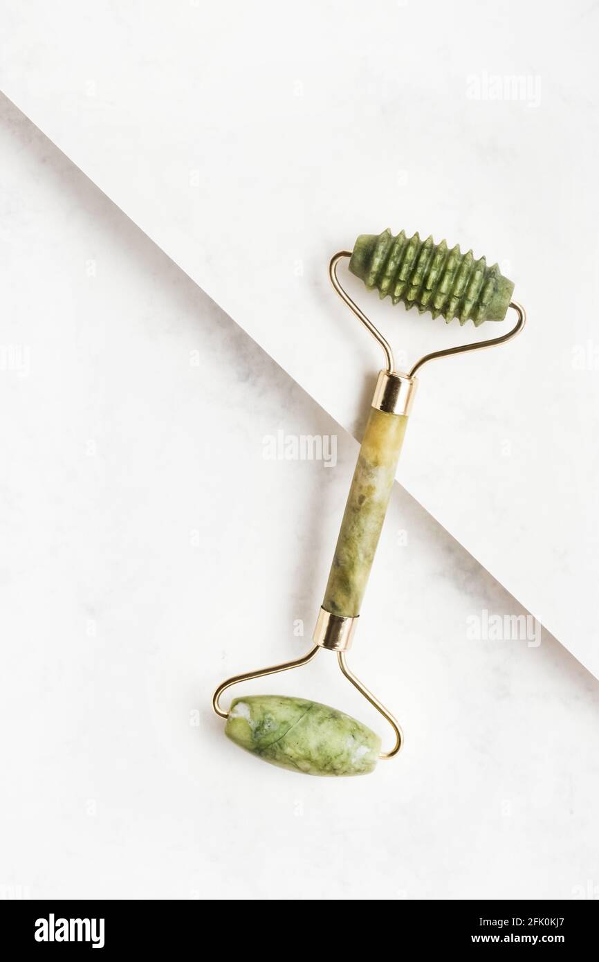 Green face roller from natural jade stone on a white background. Top view, copy space for text Stock Photo