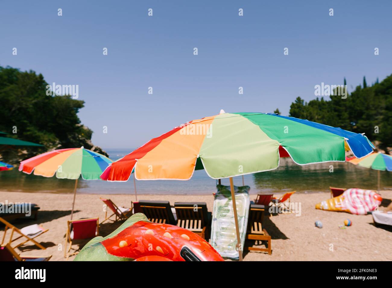 Bright colored umbrellas on the royal beach in Przno against the backdrop of the sea and green trees Stock Photo