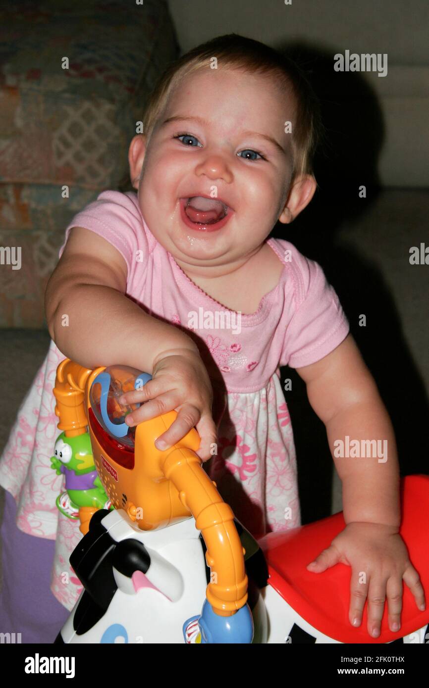 Happy 9 month old baby girl playing with her toys. Stock Photo