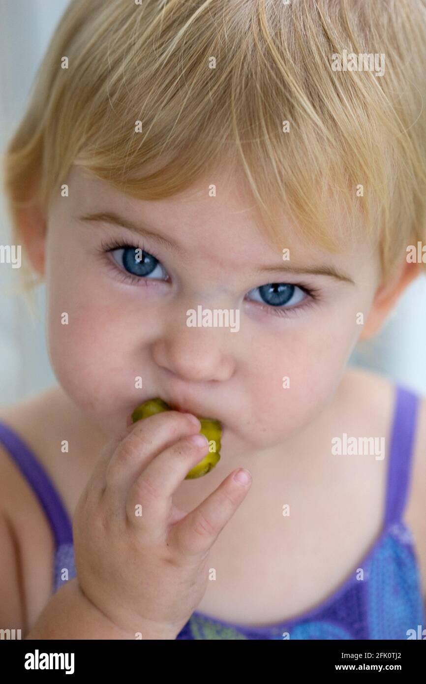 15 month old girl eating a pickle Stock Photo Alamy