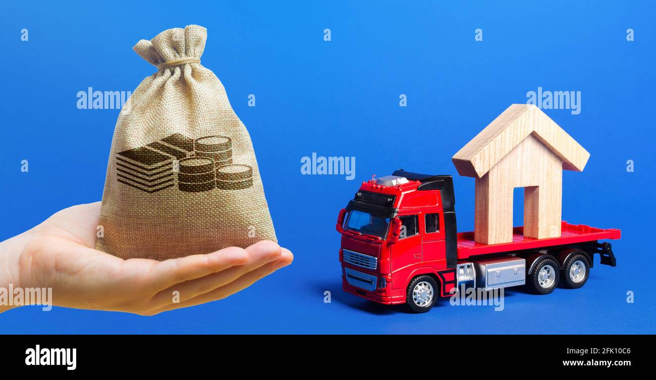 Money bag, red truck carrier with a house figure on a blue background. Cargo transportation and delivery service. A moving company. Infrastructure and Stock Photo
