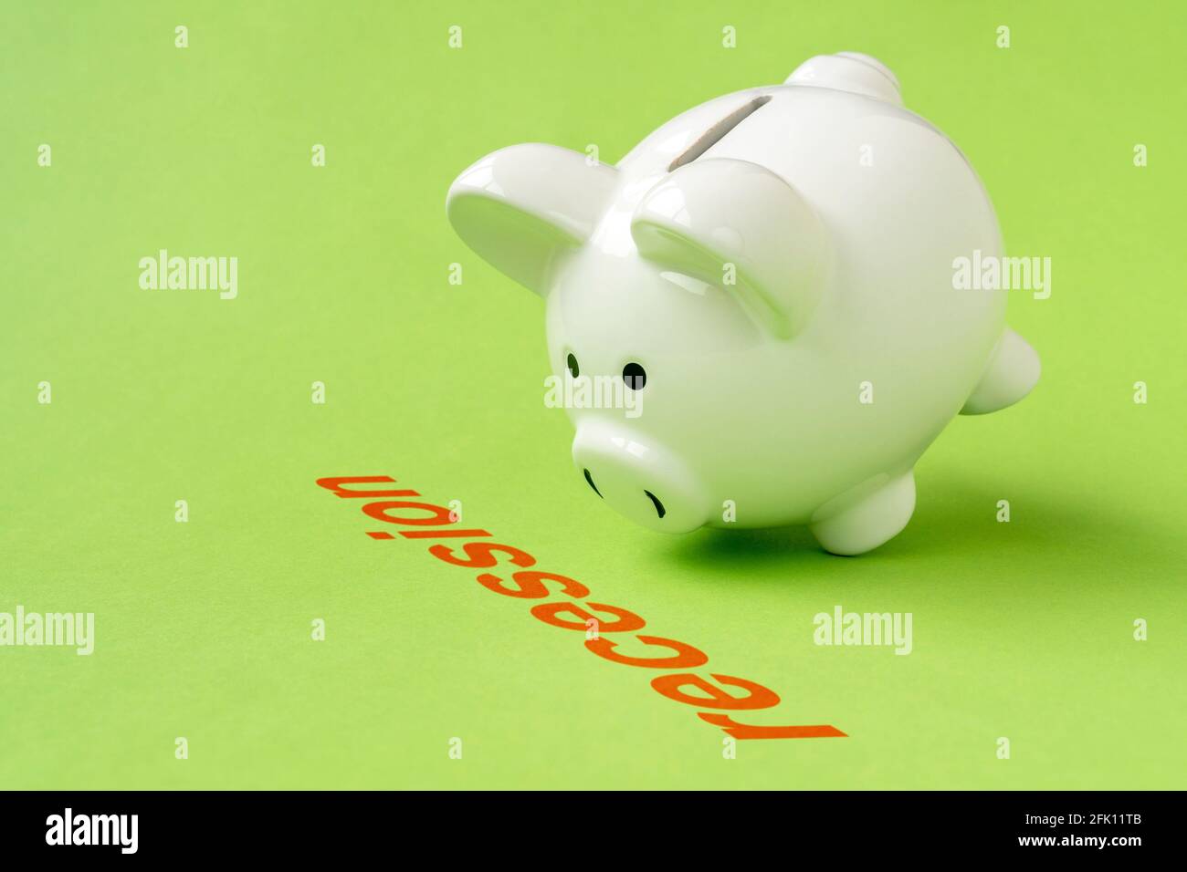 Concept financial crisis, economic depression, crash financial. Piggy bank standing near the word RECESSION. Stock Photo