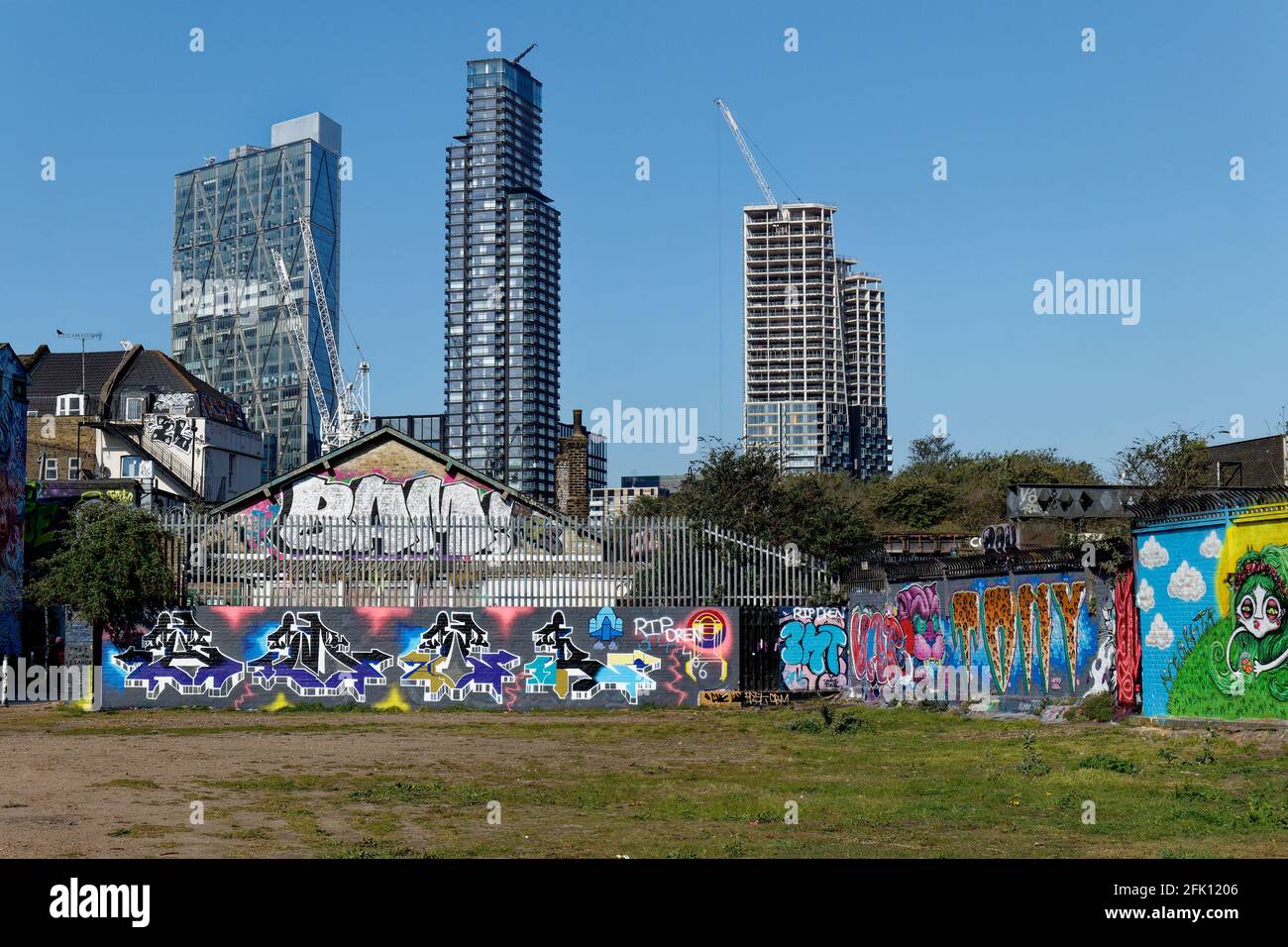 Modern high rise buildings soar above the graffitti embossed periphery of Allen Gardens in Shoreditch London Stock Photo