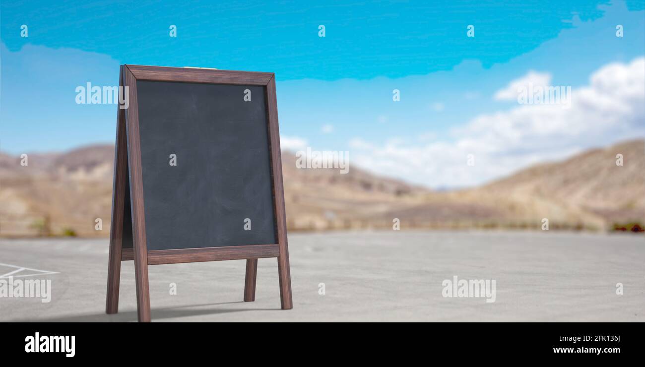 Menu board, blank empty. Black stand outdoors on the street. Wooden frame chalkboard for restaurant advertisement, announcement. Blue sky, countryside Stock Photo