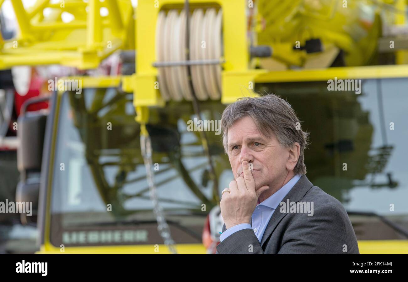 Ehingen, Germany. 27th Apr, 2021. Manfred (Manne) Lucha (Bündnis90/Die Grünen), Minister for Social Affairs and Integration of Baden-Württemberg, stands in front of a mobile crane of the engineering company Liebherr. The Liebherr plant in Ehingen was selected as a pilot plant for vaccinations by company doctors in Baden-Württemberg. The state's well-known vaccination prioritisation applies, so that employees aged 60 and over will be vaccinated as a first step. Credit: Stefan Puchner/dpa/Alamy Live News Stock Photo