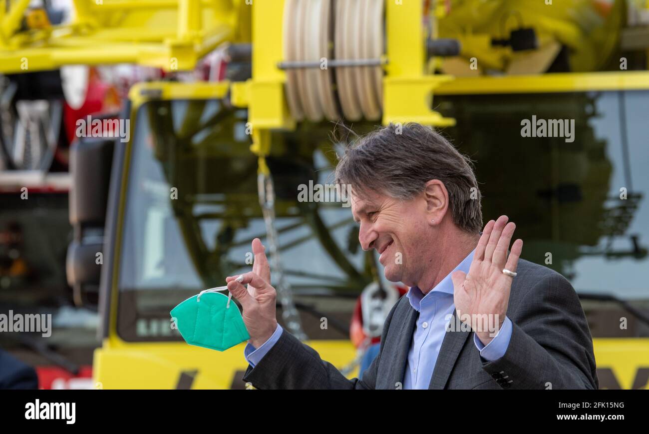 Ehingen, Germany. 27th Apr, 2021. Manfred (Manne) Lucha (Bündnis90/Die Grünen), Minister for Social Affairs and Integration of Baden-Württemberg, stands in front of a mobile crane of the engineering company Liebherr and speaks to journalists. The Liebherr factory in Ehingen has been chosen as a pilot plant for vaccinations by company doctors in Baden-Württemberg. The state's well-known vaccination prioritisation applies, so that employees aged 60 and over will be vaccinated as a first step. Credit: Stefan Puchner/dpa/Alamy Live News Stock Photo