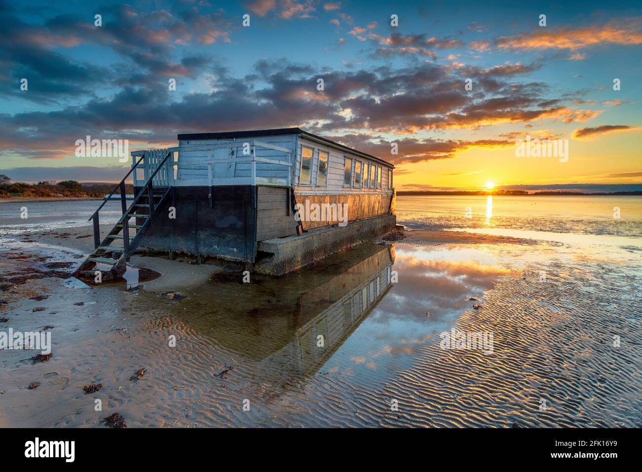 Stunning sunset over an old houseboat moored at Bramble Bush Bay at Studland on the Isle of Purbeck Stock Photo