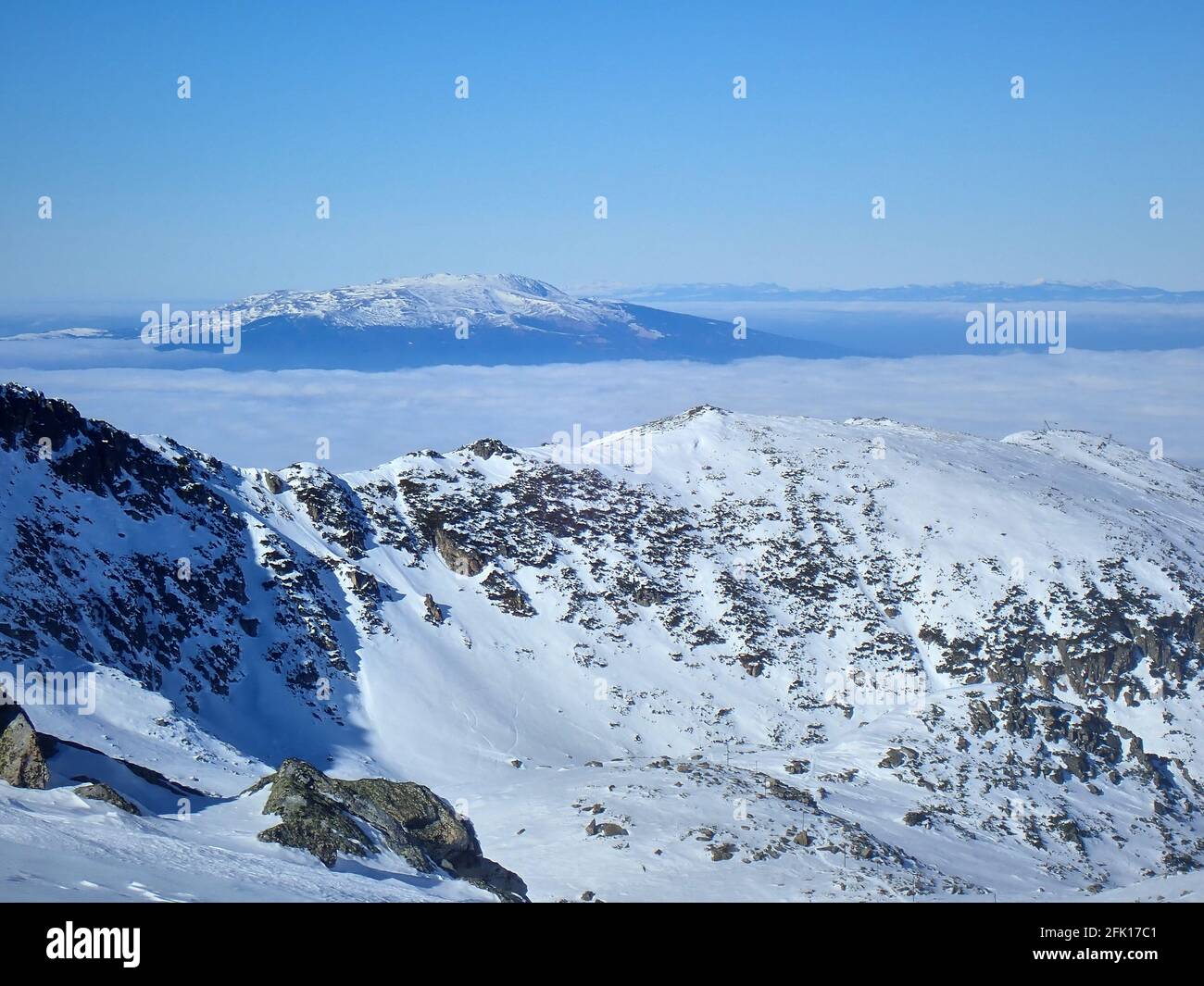 A distant view of Vitosha mountain, Bulgaria, as seen across a sea of clouds from the slopes of Musala peak, Rila mountains, Bulgaria, in winter Stock Photo
