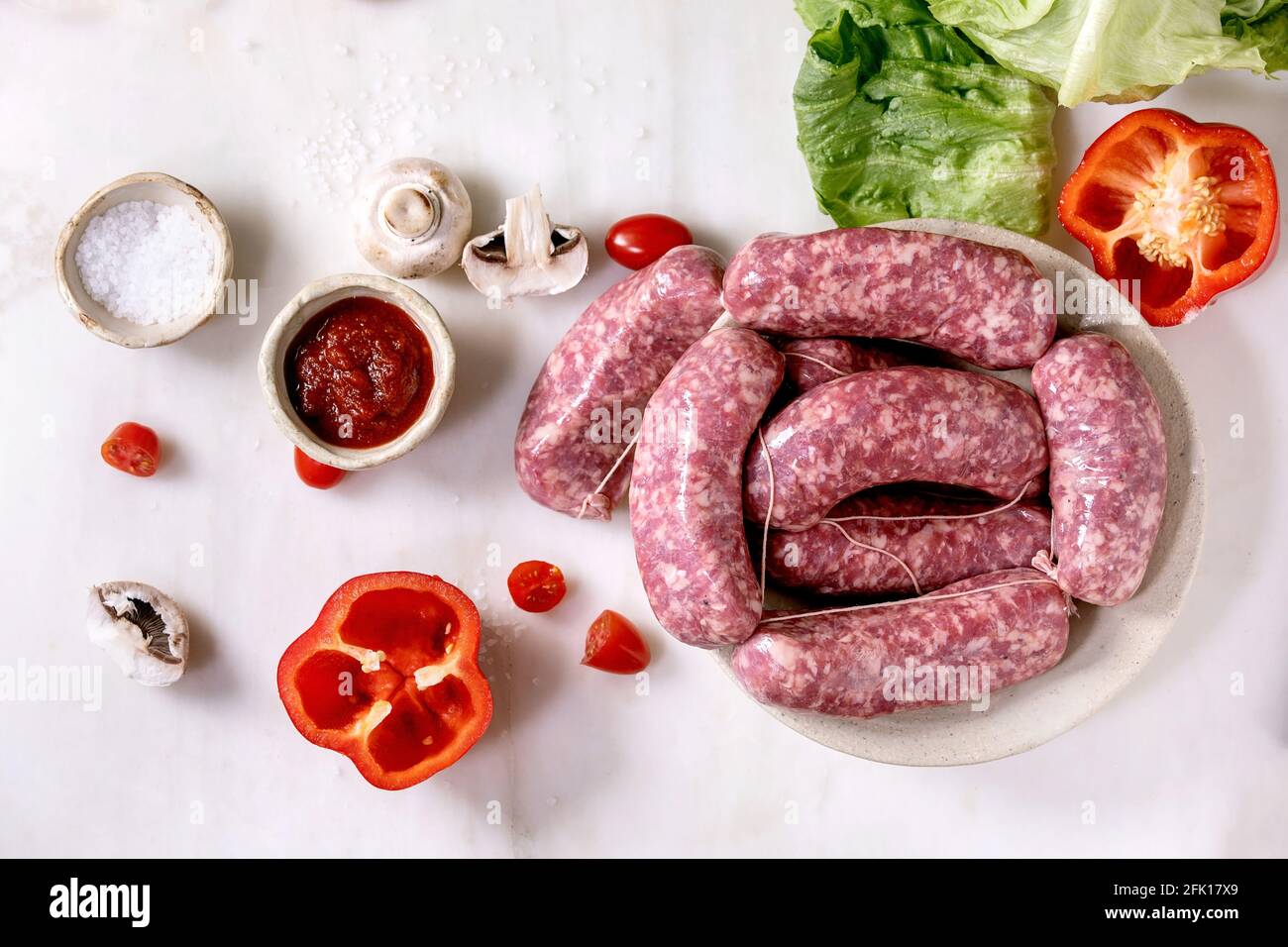 Raw uncooked italian sausages salsiccia in plate on white marble