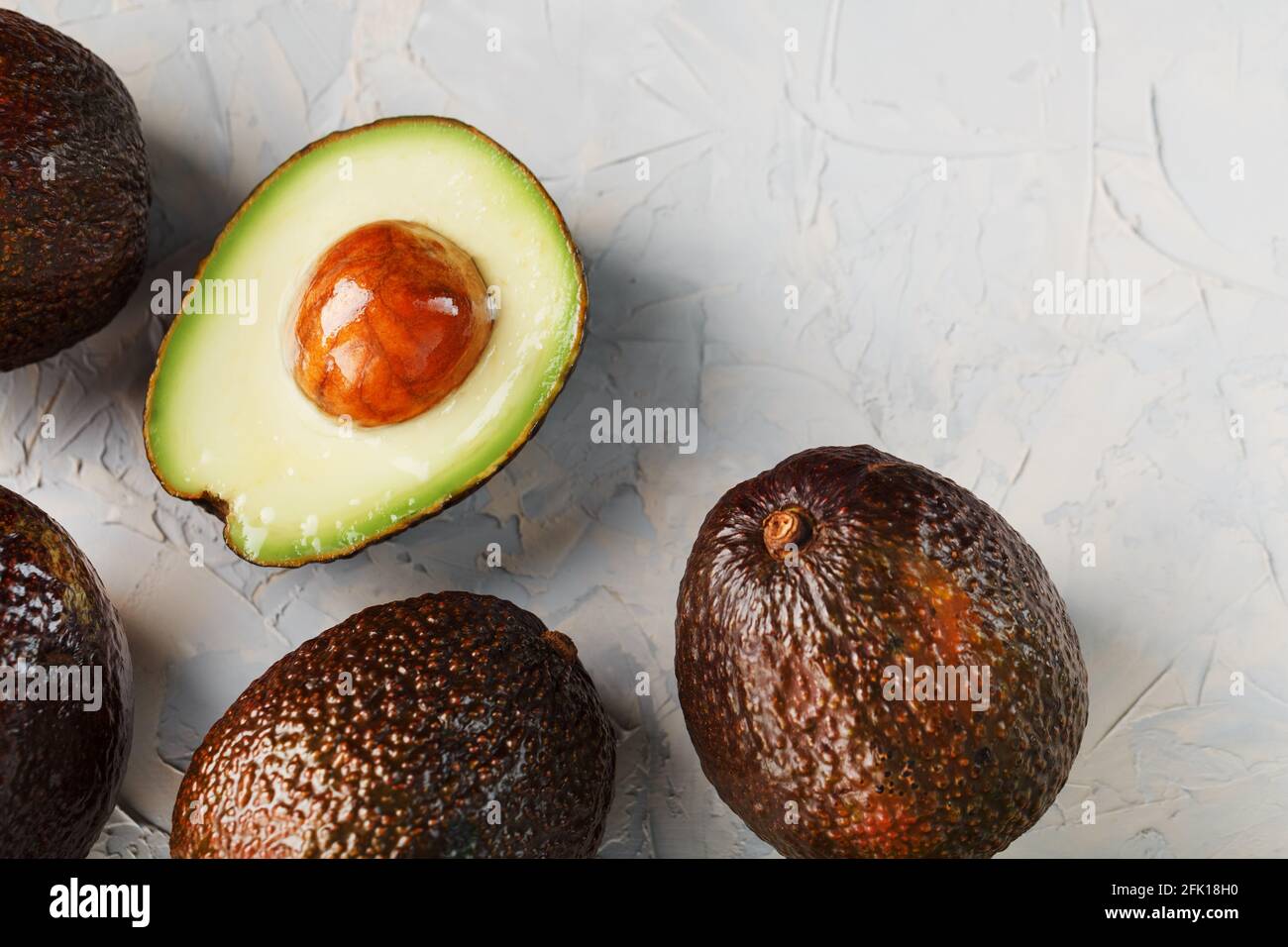 Sliced and whole organic Hass avocado on a gray background. A source of