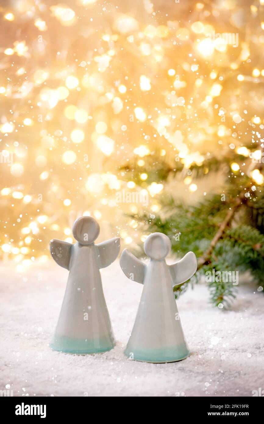 Ceramic Christmas angels. Set of two craft handmade Christmas decoration  angels on snow with bokeh holiday lights and fir tree branches Stock Photo  - Alamy