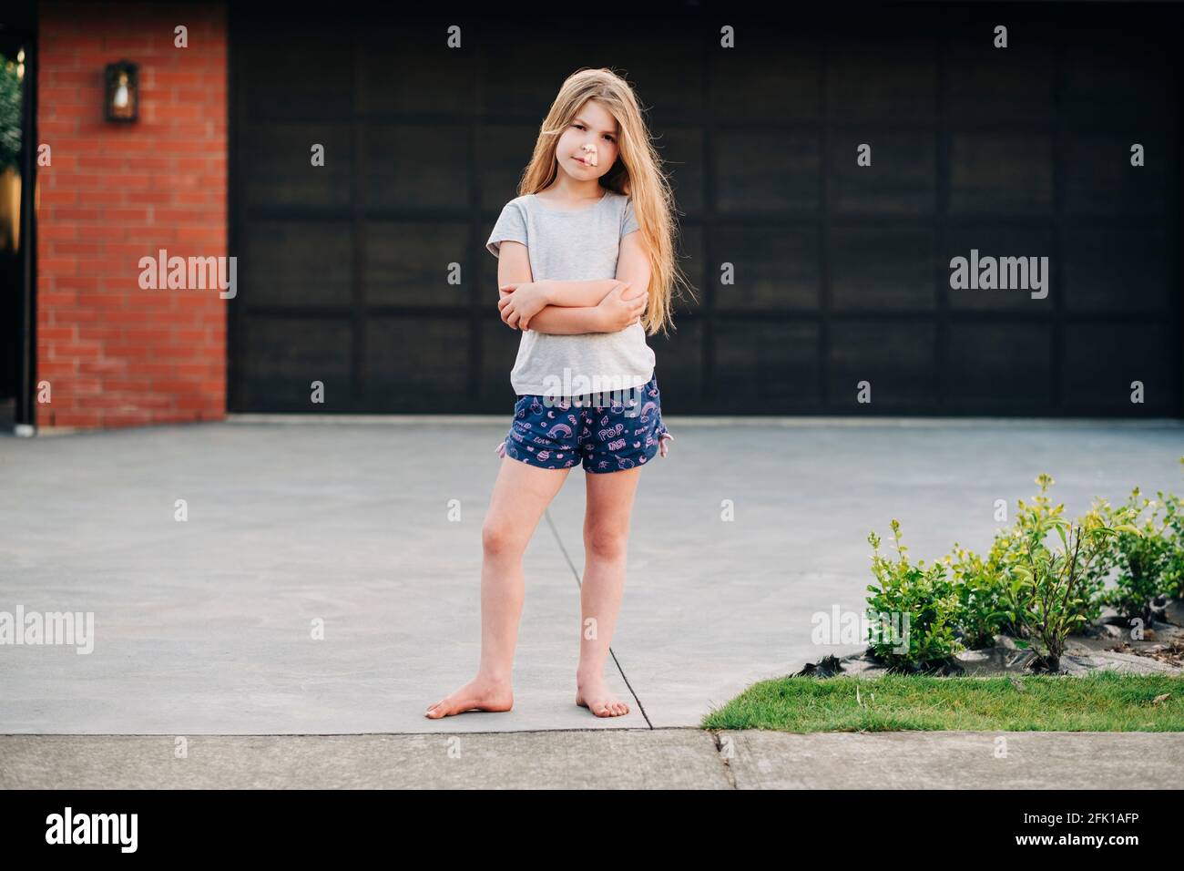 Young girl standing outside in front of garage door Stock Photo - Alamy