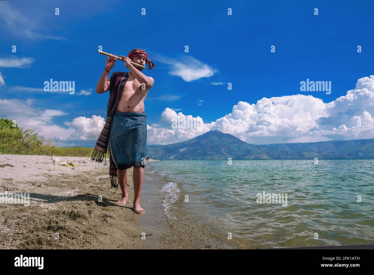 A man playing a distilled musical instrument on the shores of Lake Toba Stock Photo