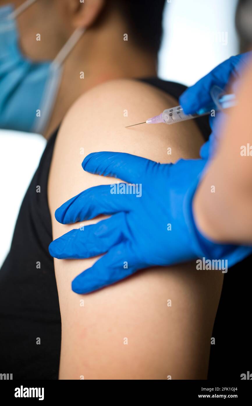 Doctor injecting vaccine into arm of patient Stock Photo