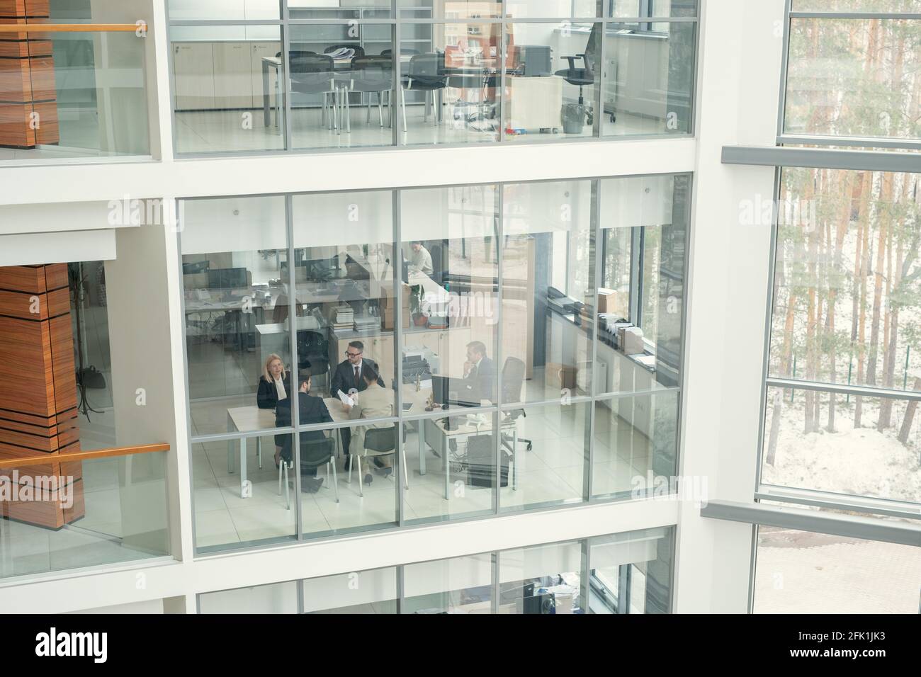 Above view of business people sitting at one table and working behind glass wall in office lobby Stock Photo