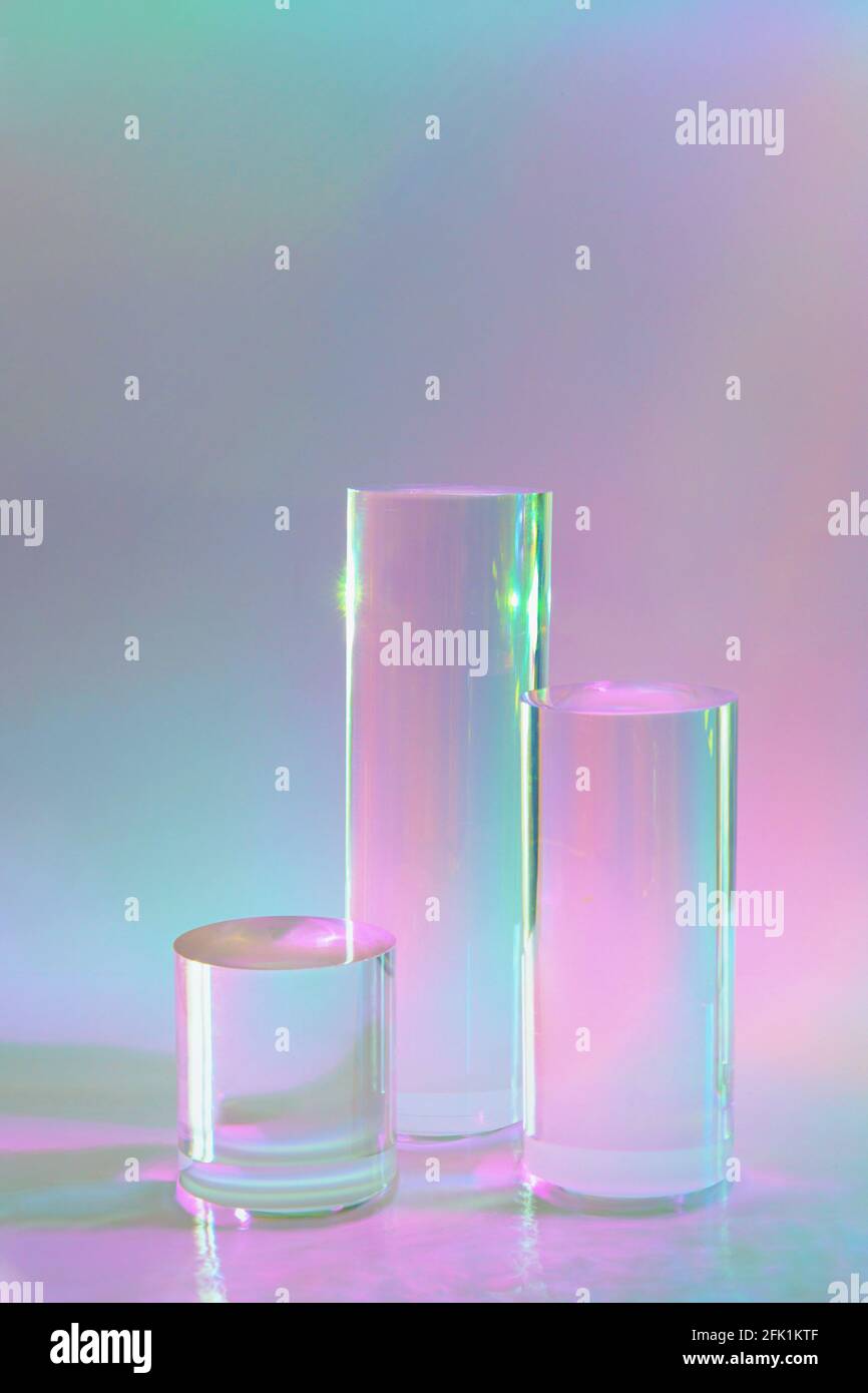 three clear glass cylinder podiums on pastel holographic colored ...