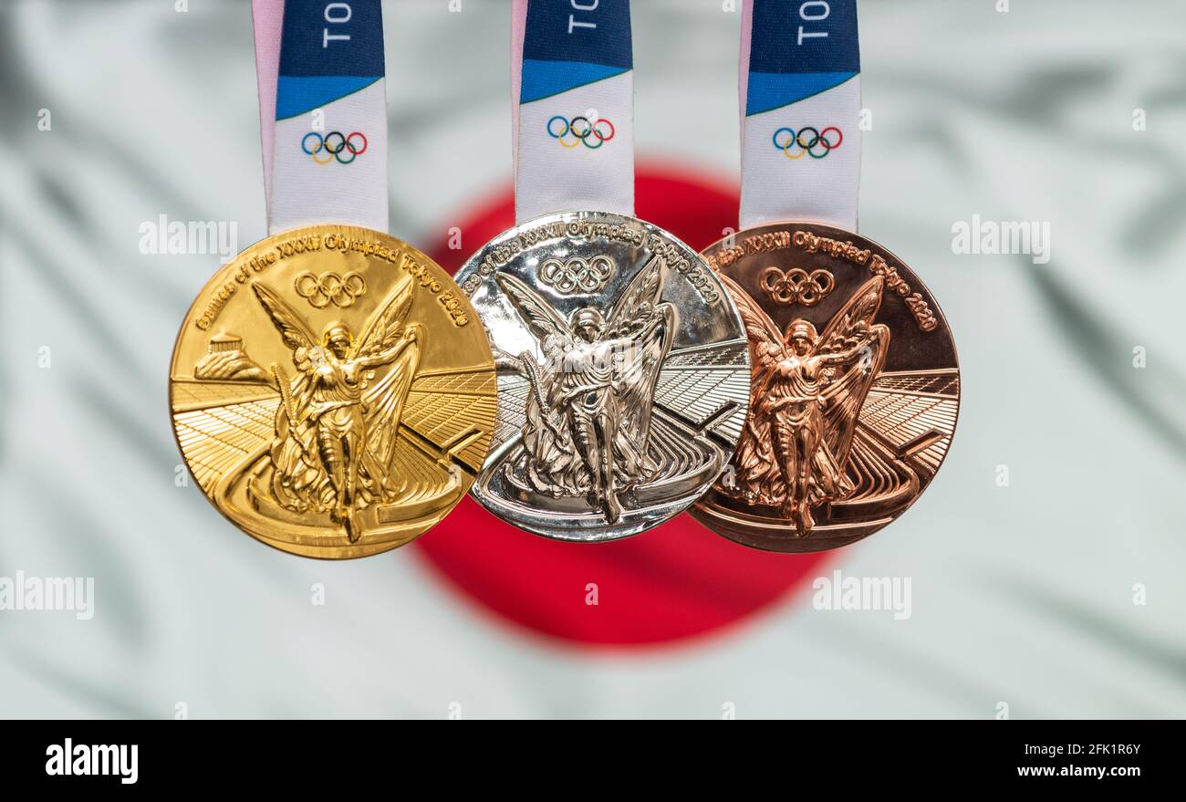 April 25, 2021 Tokyo, Japan. Gold, silver and bronze medals of the XXXII Summer Olympic Games 2020 in Tokyo on the background of the flag of Japan. Stock Photo