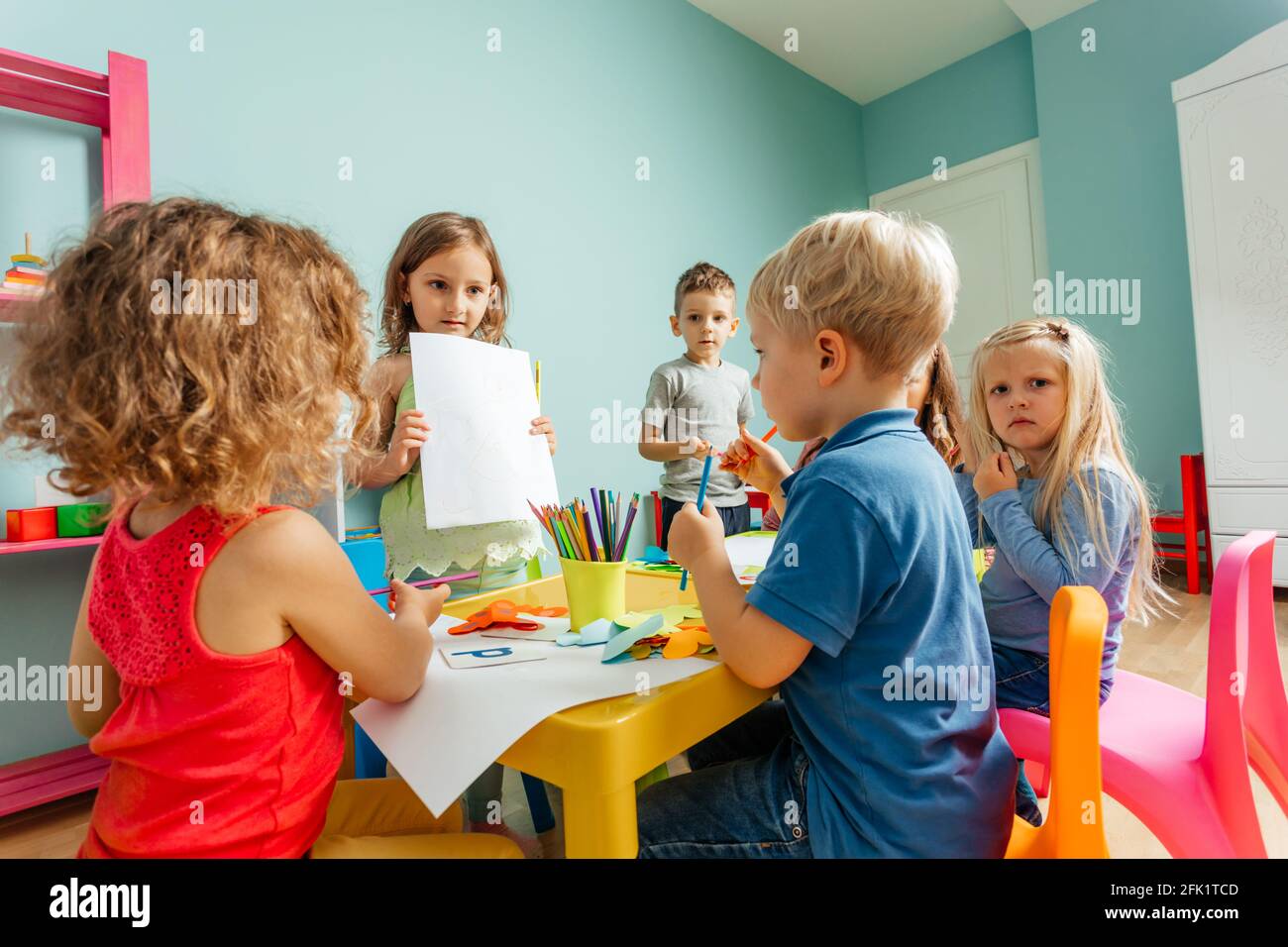 Happy little girl showing her drawing to the camera Stock Photo - Alamy