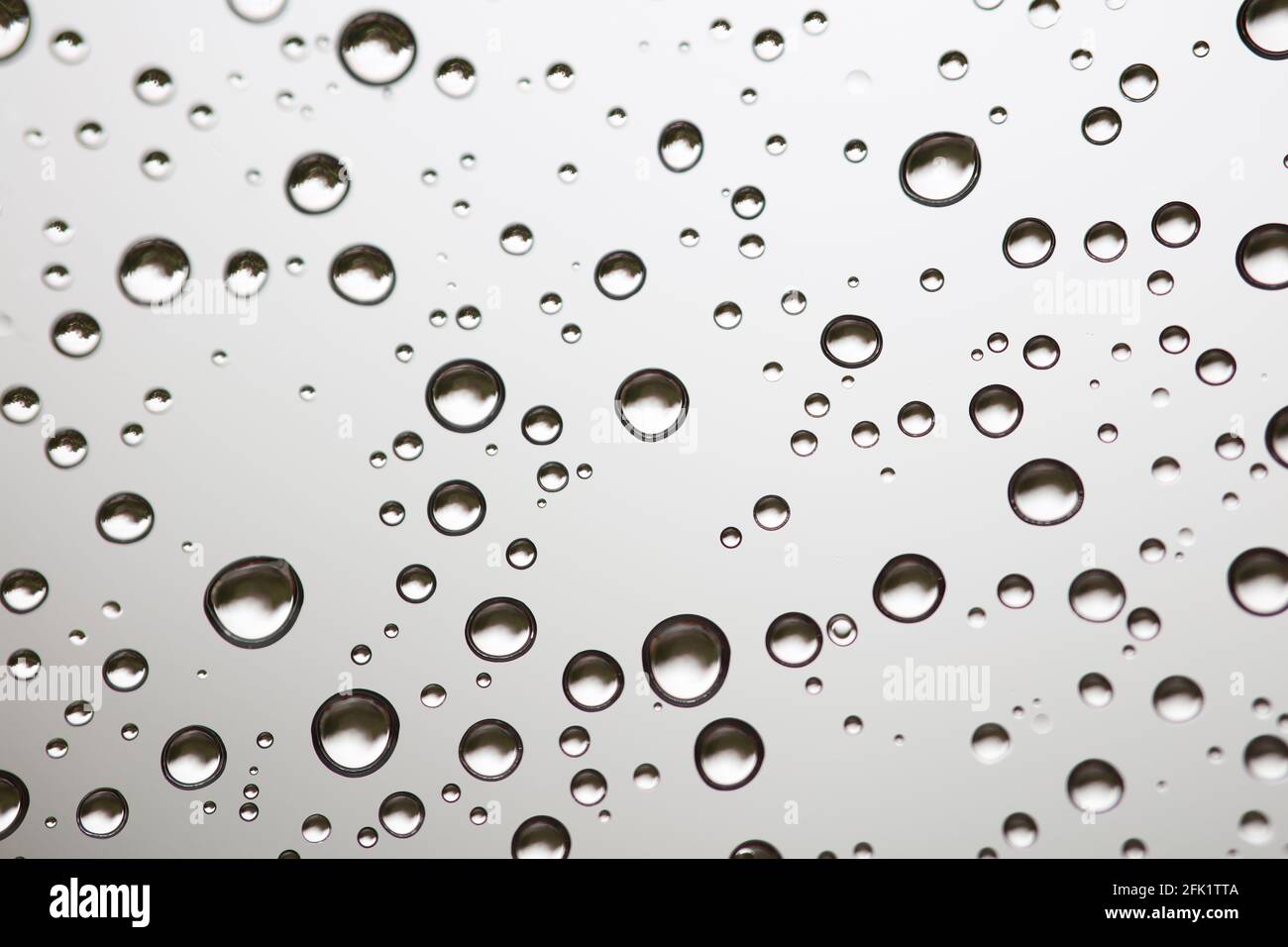 Drops of water from rainning on glass. Selective focus. white gray clouds background pattern texture. Stock Photo