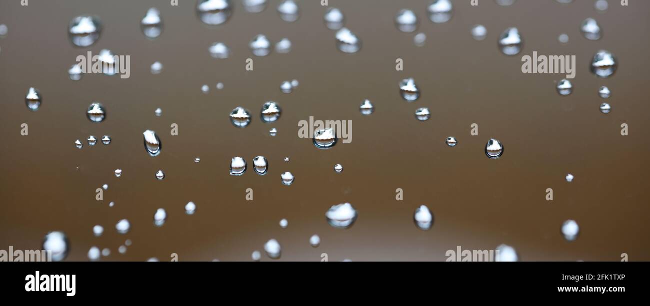 Drops of water from rainning on glass. Selective focus. white gray clouds background pattern texture. Stock Photo