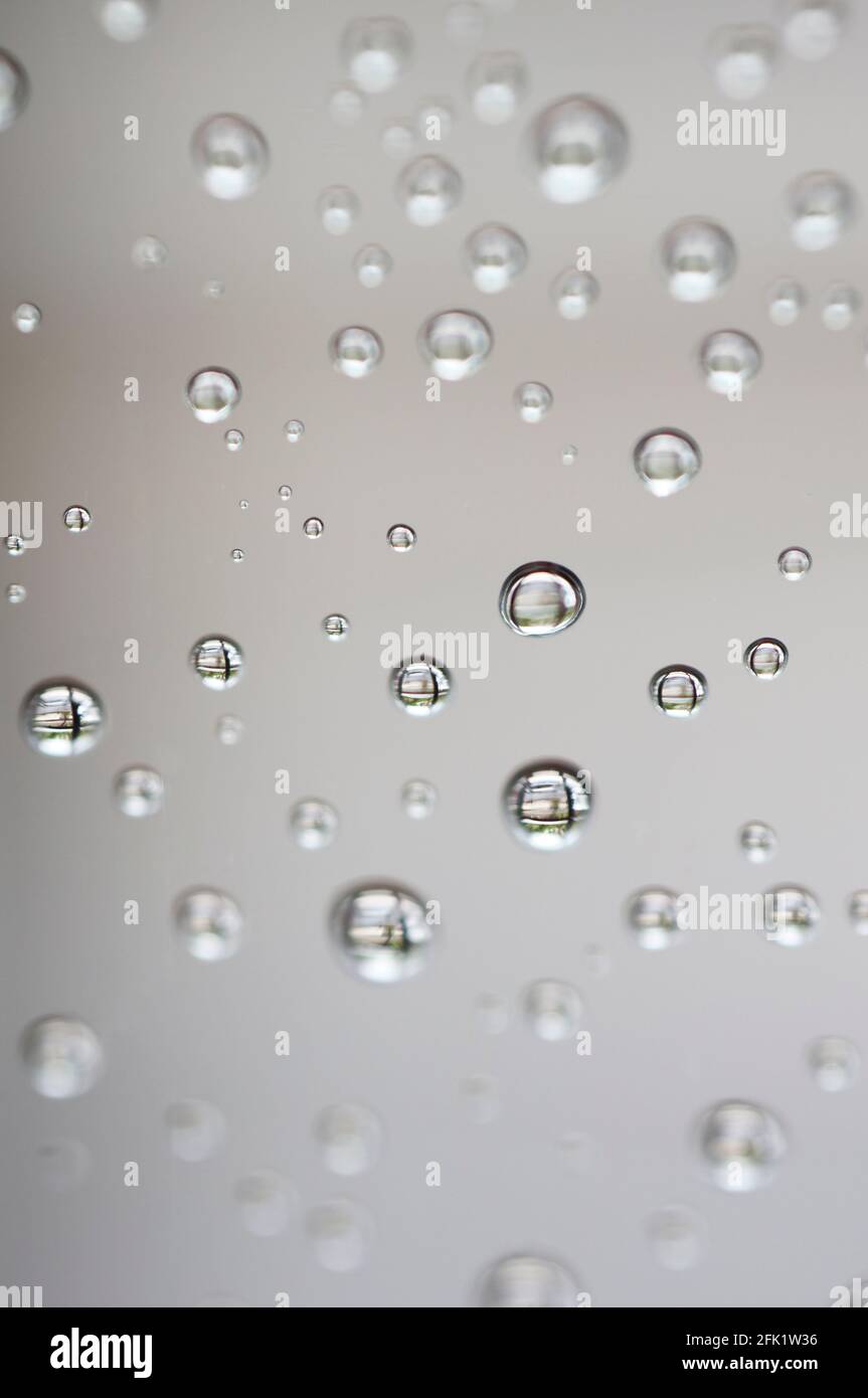 Drops of water from rainning on glass. Selective focus. white gray clouds background pattern texture. Stock Photo