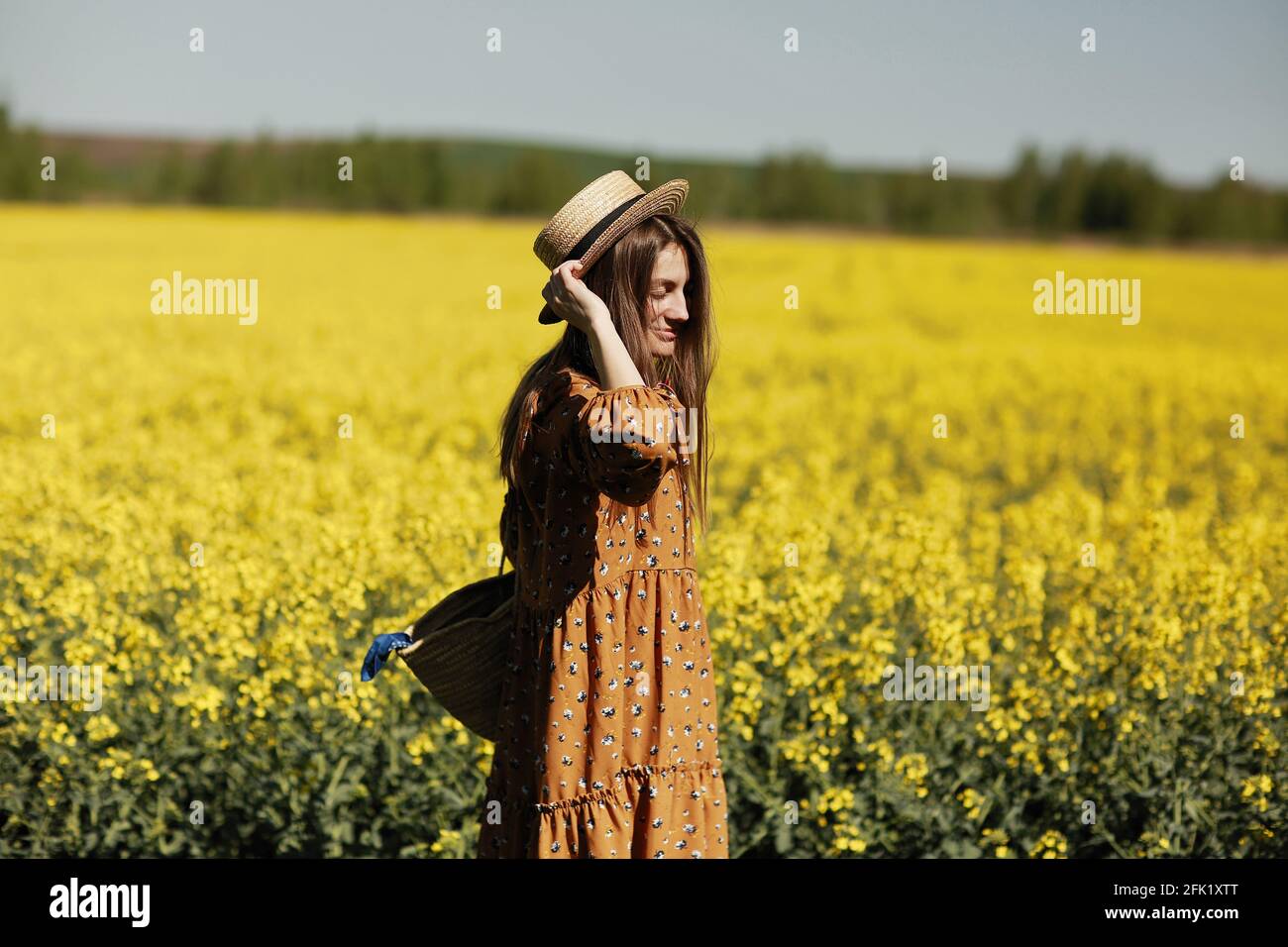 beautiful young woman walks in a field of yellow rapeseed. Girl ...