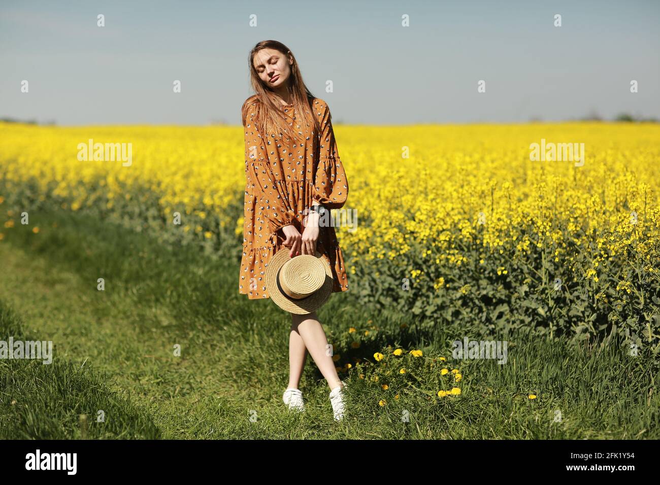 beautiful young woman walks in a field of yellow rapeseed. Girl ...