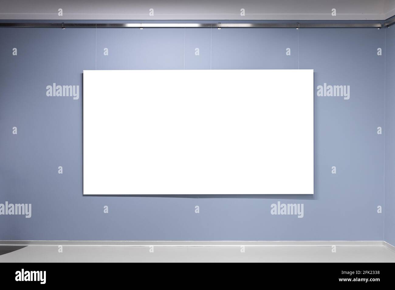 Blank white poster with copy space area hangs on blue wall in an exhibition hall. Front view, background photo Stock Photo
