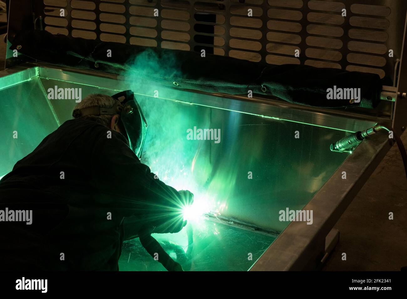Welder wearing gloves and mask. Photography with welding sparks and smoke. Stock Photo