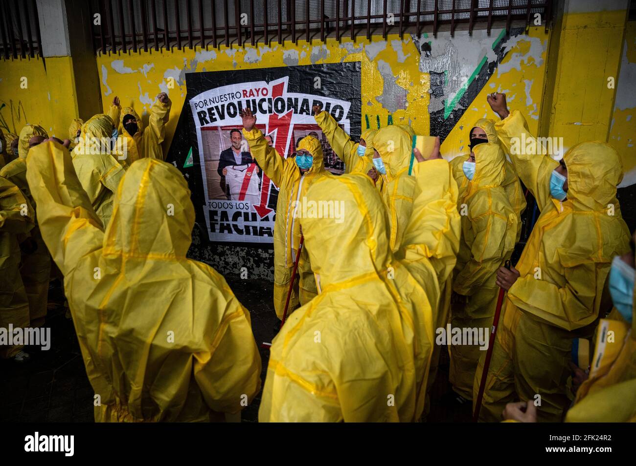 Madrid, Spain. 27th Apr, 2021. Protesters wearing personal protective equipment raising hands after placing a placard to protest against the last visit to a match in the Rayo Vallecano Stadium of Santiago Abascal, leader of far right wing VOX party, and Rocio Monasterio, candidate for the next regional elections of Madrid. Protesters, members of Bukaneros group, are performing an action under the slogan 'let's disinfect our stadium' shouting slogans against fascism and against far right wing VOX party. Credit: Marcos del Mazo/Alamy Live News Stock Photo
