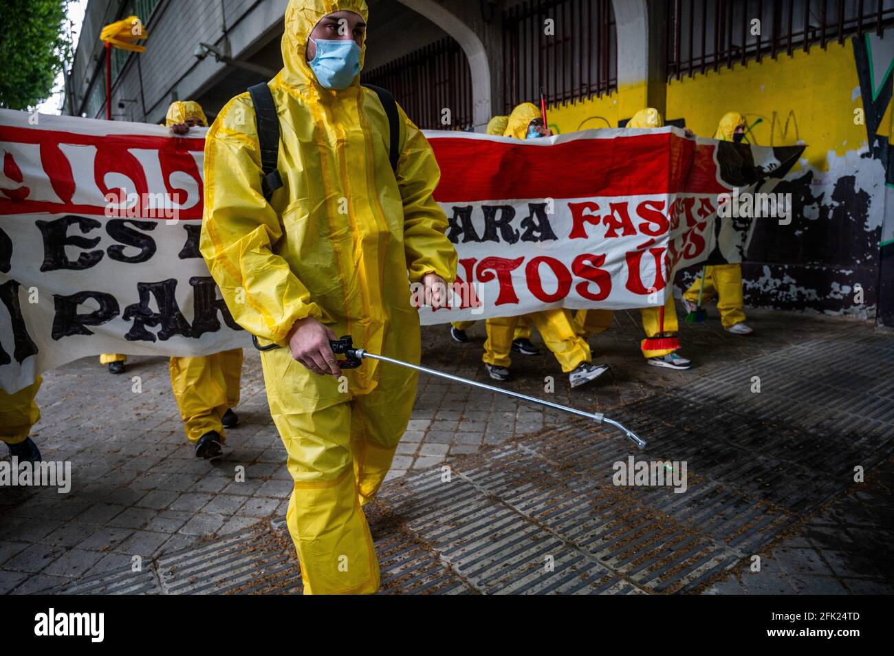 Madrid, Spain. 27th Apr, 2021. Protesters wearing personal protective equipment carrying a banner and disinfection equipment to protest against the last visit to a match in the Rayo Vallecano Stadium of Santiago Abascal, leader of far right wing VOX party, and Rocio Monasterio, candidate for the next regional elections of Madrid. Protesters, members of Bukaneros group, are performing an action under the slogan 'let's disinfect our stadium' shouting slogans against fascism and against far right wing VOX party. Credit: Marcos del Mazo/Alamy Live News Stock Photo