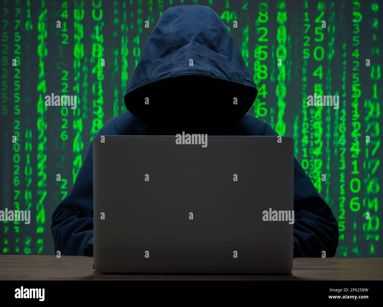 The hacker is in front of his computer. Digital figures in the background Stock Photo