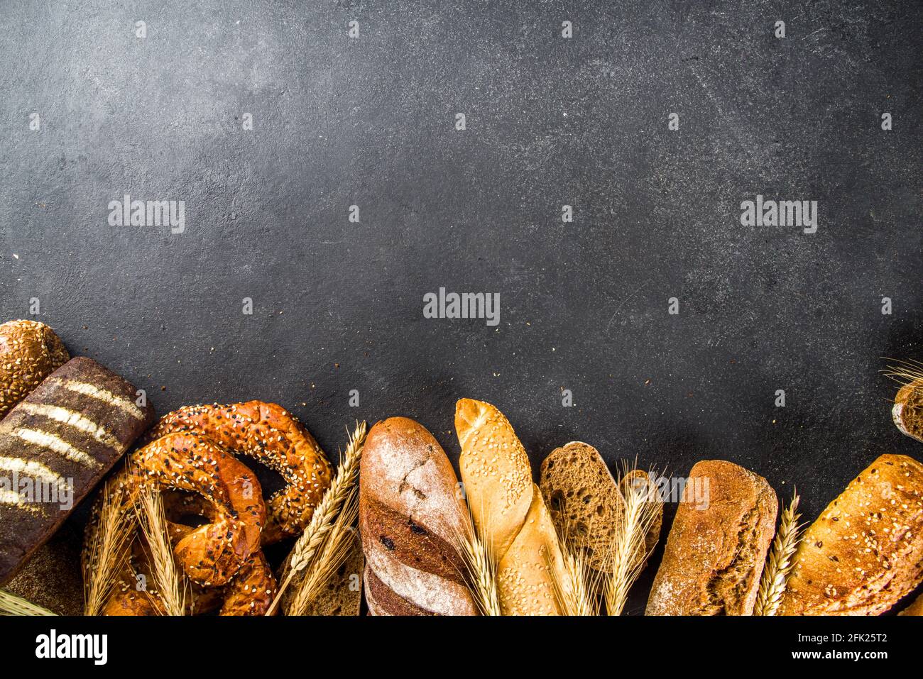 Assortment of various delicious freshly baked bread, on black concrete background top view copy space Stock Photo