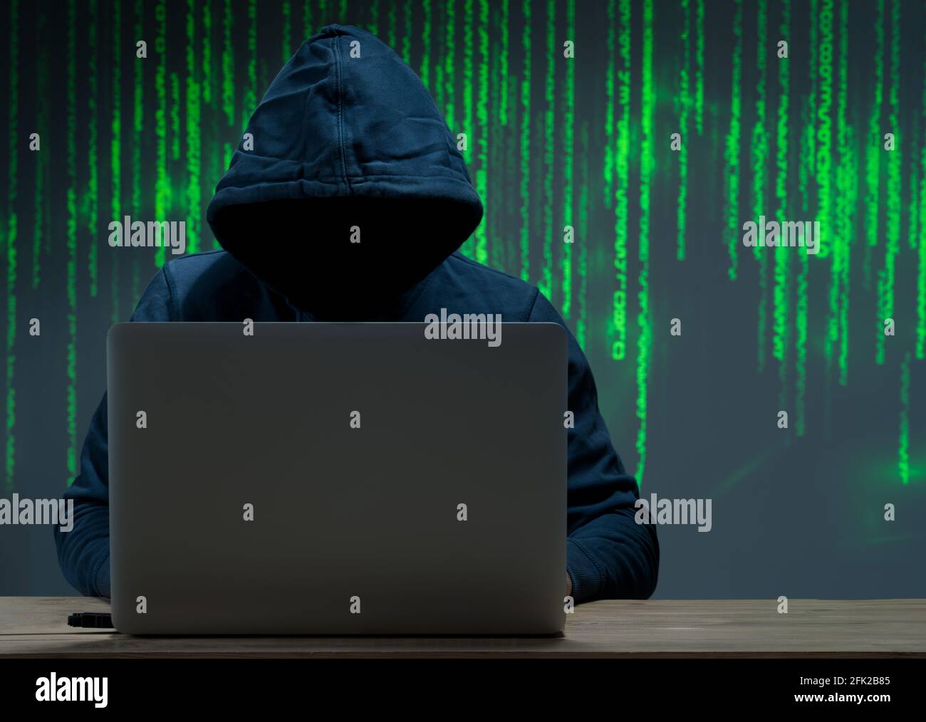 The hacker is in front of his computer. Digital figures in the background Stock Photo