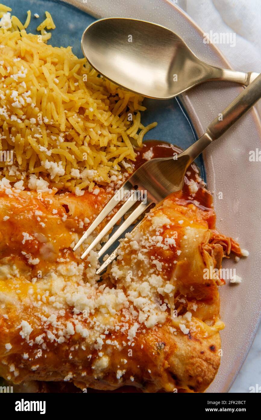 Traditional Mexican enchiladas dinner served with rice and refried pinto beans Stock Photo