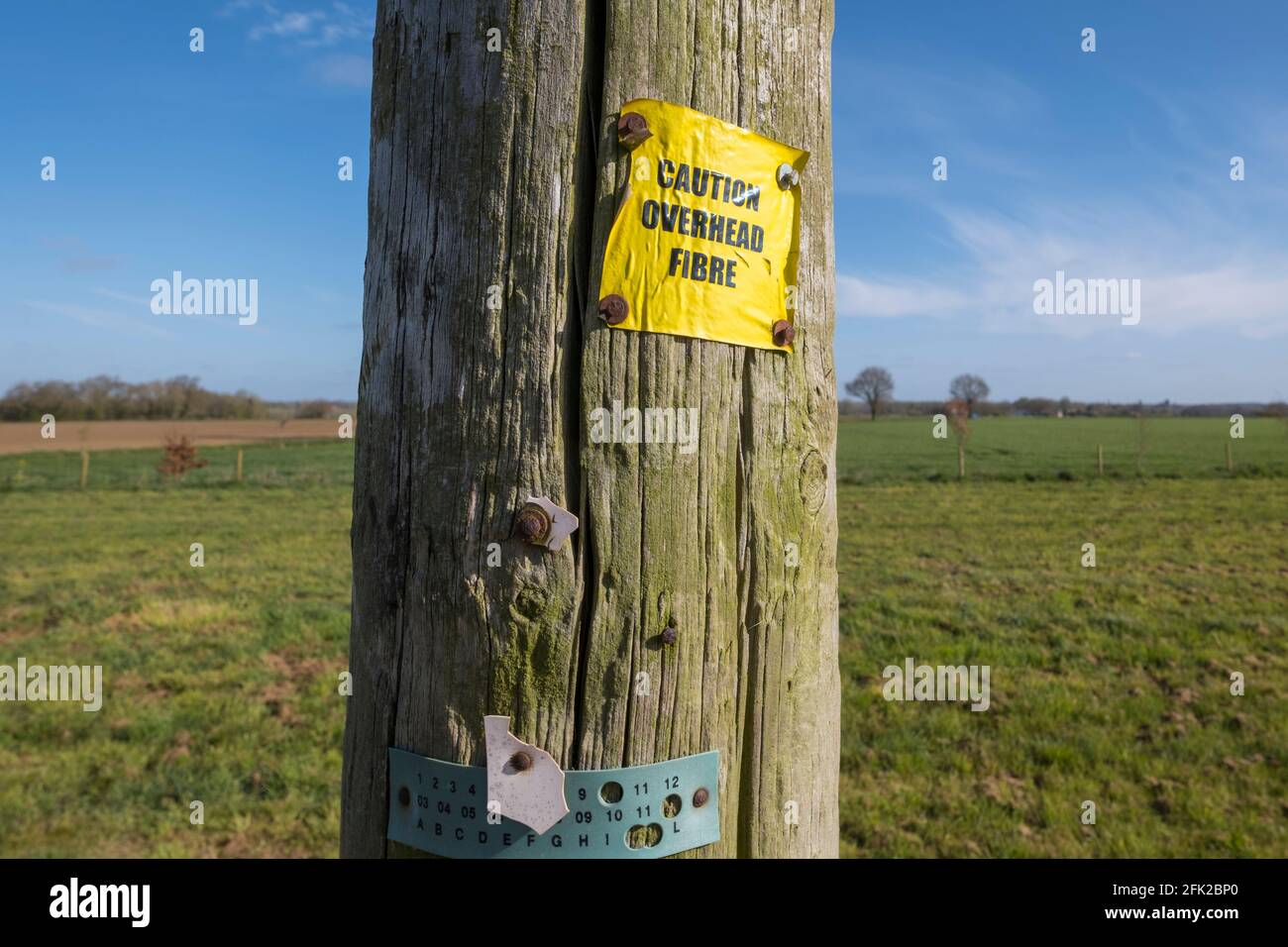 Rural broadband illustrated by a 'caution overhead fibre' sign in the Suffolk, UK country side. Stock Photo